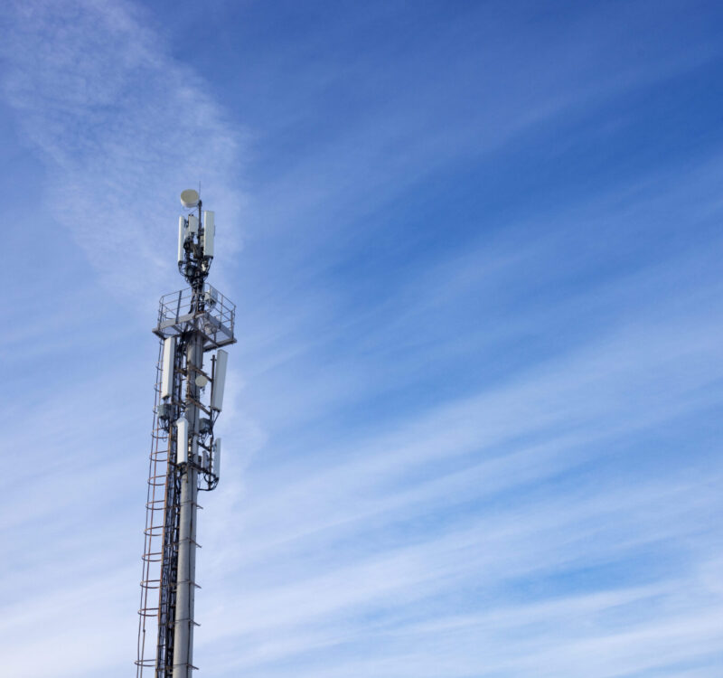 A tower telecommunications tower with antennas, against a background of blue sky with light clouds